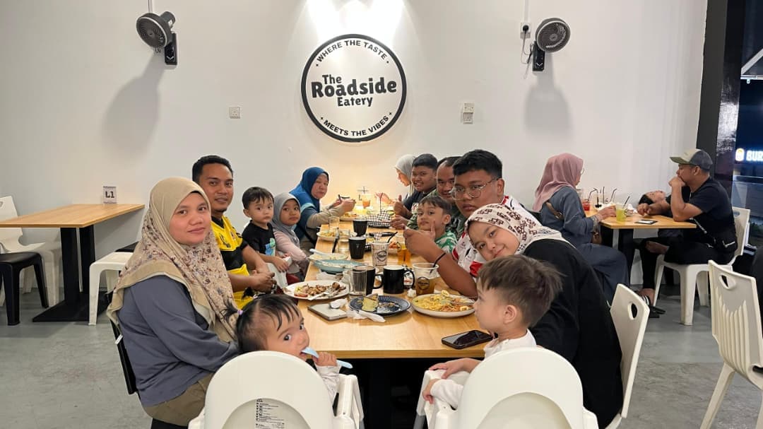 A family gathered for a meal beneath The Roadside Eatery sign